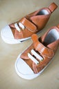 Top view closeup of a brown pair of shoes for a baby on a white surface