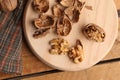 Top view closeup of cracked walnuts with shells on a round board and checkered cloth on the side Royalty Free Stock Photo