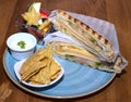 Top view closeup of a delicious cheese and ham sandwich, nachos and a tiny bowl of fruit on a plate