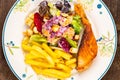 Top view closeup of delicious homemade salmon steak with caesar salad and french fried Royalty Free Stock Photo