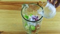 Top view closeup on mand hands pours clear water from glass cup into blender chalice