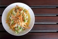 Top view, closeup papaya salad with raw blue swimming crab in white plate on wood table background is famous food in Thailand Royalty Free Stock Photo