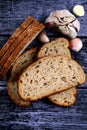 Top view closeup of a sliced loaf of brown bread and garlic cloves on a wooden table Royalty Free Stock Photo