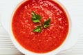 Top view closeup of a white bowl of tomato soup with parsley on a white wooden background Royalty Free Stock Photo