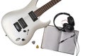 Top view of closeup of white electric guitar, two mediators, open notebook, pen and headphones. Workspace of musician. Isolated on