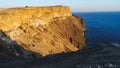 Top view of coastal cliff with blue sea at sunset. Shot. Beautiful view of golden sunset light on rocky cliffs of sea Royalty Free Stock Photo