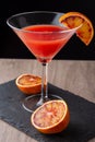 Top view of cocktail glass with blood orange martini, half orange, on black slate and wood Royalty Free Stock Photo