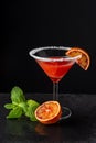 Top view of cocktail glass with blood orange martini and sugar, with half orange and mint, on black background, vertical Royalty Free Stock Photo