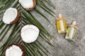 Top view of coconut oil in glass bottles on grey textured background with palm leaf and cracked coconuts. Royalty Free Stock Photo