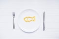 Top view Cod Liver Oil Capsules, Omega 3, Vitamin D in the fish shape on white round plate served with knife and fork on the white Royalty Free Stock Photo