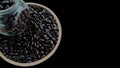 Top view, coffee beans from a glass bottle on a wooden plate on a black background Royalty Free Stock Photo