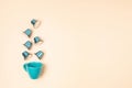 Top view of coffee capsules and cup over beige background with copy space. Morning dose of caffeine, energy, flavor