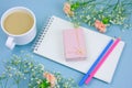 coffee with cream cup, notebook,pencils and pink gift box with flowers frame on a blue background Royalty Free Stock Photo