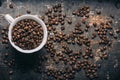 Top view of coffee cup on coffee bean texture and black rustic background. Hot beverage on vintage dark table Royalty Free Stock Photo