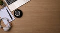 Coffee cup, headphone, notebook and laptop on wooden desk.