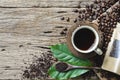 Top view Coffee in a cup, placed on a wooden plate with a wooden spoon,  coffee beans, and leaves as an element on the old wooden Royalty Free Stock Photo