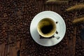 Top view of coffee cup on saucer with grass flowers and roasted coffee beans on wooden table
