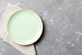 Top view on colored background empty round green plate on tablecloth for food. Empty dish on napkin with space for your Royalty Free Stock Photo
