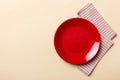 Top view on colored background empty round red plate on tablecloth for food. Empty dish on napkin with space for your Royalty Free Stock Photo