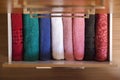 Top view of colored towels stored and organized in a wooden clothes guard drawer.