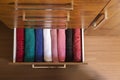 Top view of colored towels stored and organized in a wooden clothes guard drawer.