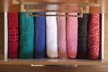 Top view of colored towels stored and organized in a wooden clothes guard drawer.