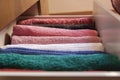 Top view of colored towels stored and organized in a wooden clothes guard drawer.