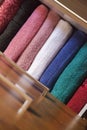 Top view of colored towels stored and organized in a wooden clothes guard drawer.