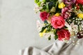 Top view of a colorful bouquet of beautiful flowers in the corner and gray blurry background with a piece of fabric