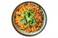 Top view of a colorful bowl of Mexican rice and beans garnished with cilantro presented on a white surface,