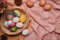 Colorful Easter eggs in wicker basket on wooden table. Ester concept.