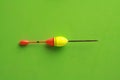 Top view of a colorful fishing rod bobber on a green background