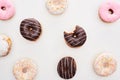 Top view of colorful glazed delicious doughnuts and bitten one on white background.