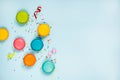 Top view of colorful macaroons, sugar sprinkles and party ribbons arranged over blue background. Copy space.