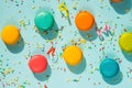 Top view of colorful macaroons, sugar sprinkles and party ribbons over blue background. Abstract party food background.
