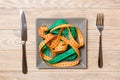 Top view of colorful measuring tapes on plate in the form of spaghetti with knife and fork on wooden background. Weight loss and Royalty Free Stock Photo