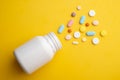 Top view colorful medical pills and white bottle on yellow background