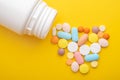 Top view colorful medical pills and white bottle on yellow background