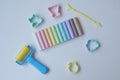 Top view colorful modelling clay, plastic rolling pin, four plastic cutters and a yellow plastic craft tool, on white background,