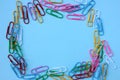 Top view of colorful paper clips on blue background. Back to school or office concept