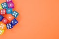 Top view of colorful plastic dice against an orange background with space for text