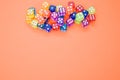 Top view of colorful plastic dice against an orange background with space for text