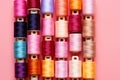 Top view of colorful sewing threads on pink background, copy