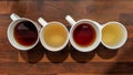 Top view of colorful teas filled in white cups and placed on wooden counter in the kitchen, served and ready to drink Royalty Free Stock Photo