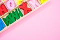 Top view of colorful wooden letters in their case, placed on a pink surface Royalty Free Stock Photo