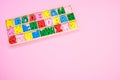 Top view of colorful wooden letters in their case, placed on a pink surface Royalty Free Stock Photo