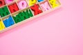 Top view of colorful wooden letters in their case, placed on a pink surface Royalty Free Stock Photo