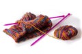 Top view of a colourful woolen cloth, needles and a skein on white