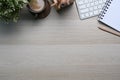 Top view of comfortable workplace with notebook, coffee cup, plant, keyboard and copy space on wooden table. Royalty Free Stock Photo