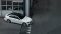 Top view of a compact white executive car with beautiful alloy wheels parked in industrial area